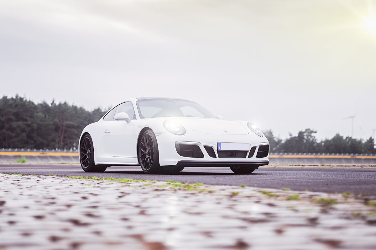 Weißer Porsche fährt auf einer Straße.