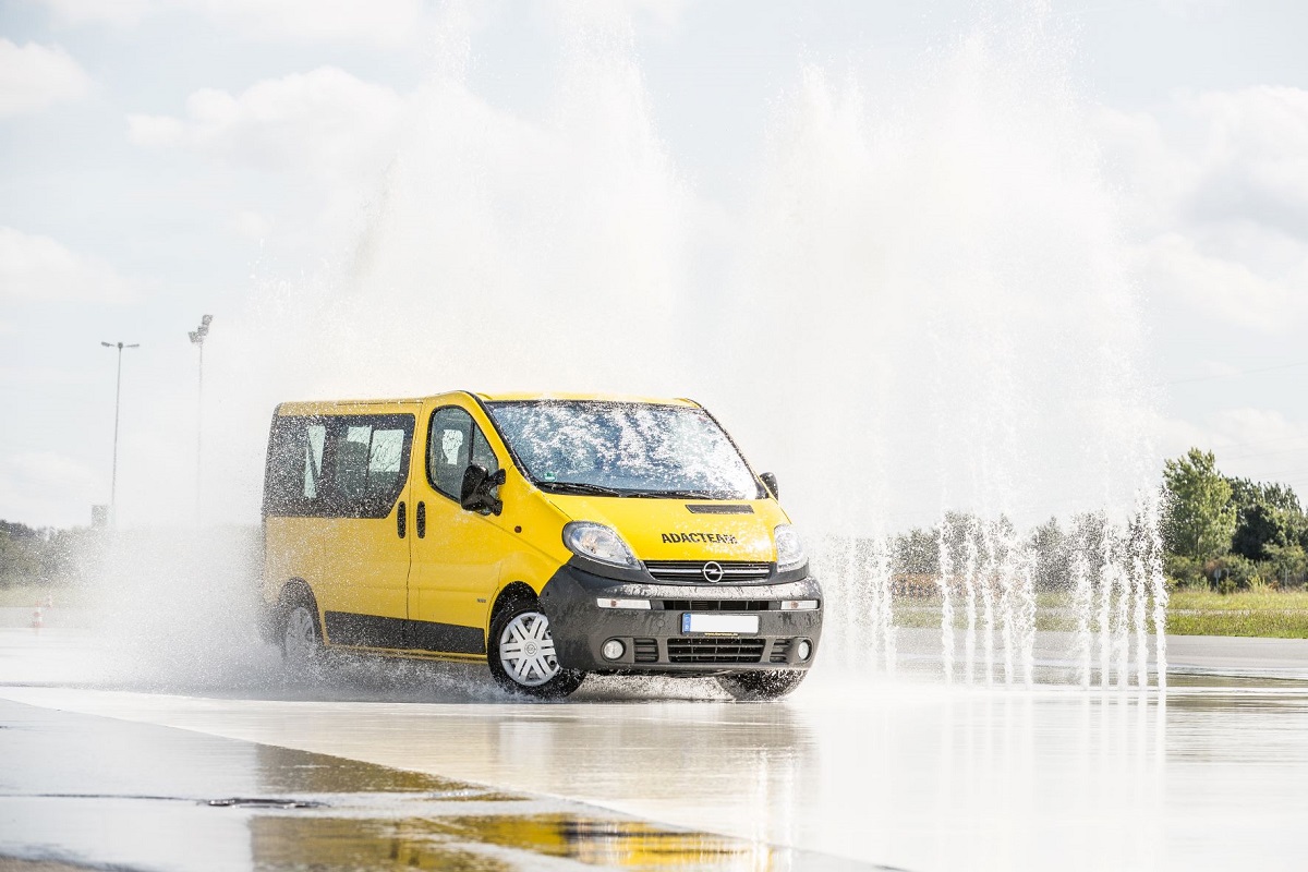 Ein gelber ADAD Transporter fährt durch eine künstlich erzeugte Regenwand.