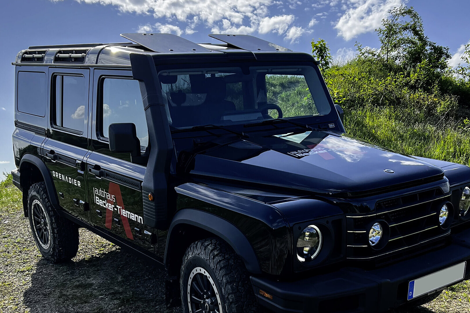 Schwarzer Geländewaagen fährt über einen Hügel.